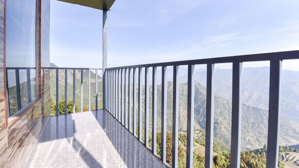 Un balcón con barandilla de metal que da a un paisaje montañoso.