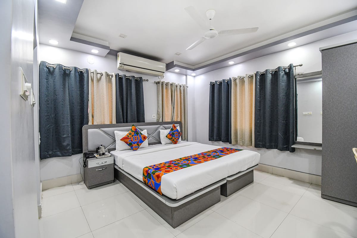 A modern hotel room with a large bed, bedside tables, a wardrobe, and a ceiling fan.