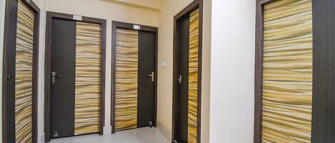 A hallway with three doors, each with a number plate and a striped pattern.