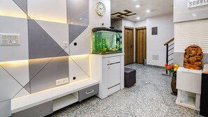 A modern interior with a fish tank, a clock, and a statue. - Fabexpress Scholer Motel (Kolkata)