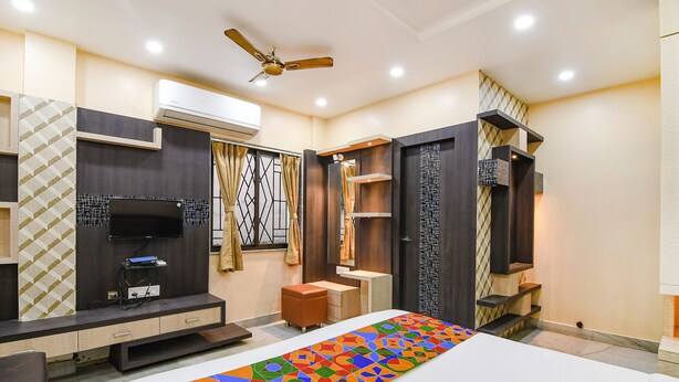 A modern bedroom with a bed, a TV, a desk, and a wardrobe. - Fabexpress Scholer Motel (Kolkata)