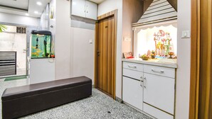 A room with a bench, a fish tank, a cabinet, and a shrine with religious icons. - Fabexpress Scholer Motel (Kolkata)