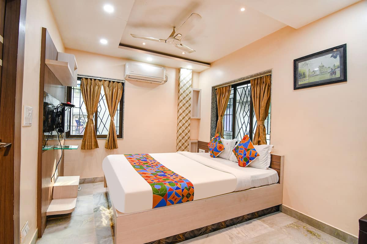 A bedroom with a bed, curtains, a ceiling fan, and a framed picture on the wall.