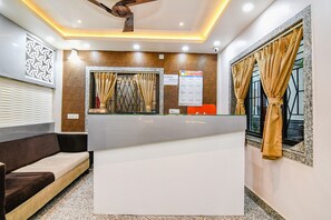 Ein Empfangsbereich mit einer Rezeption, einer Couch, einem Deckenventilator und einem Bulletin Board.