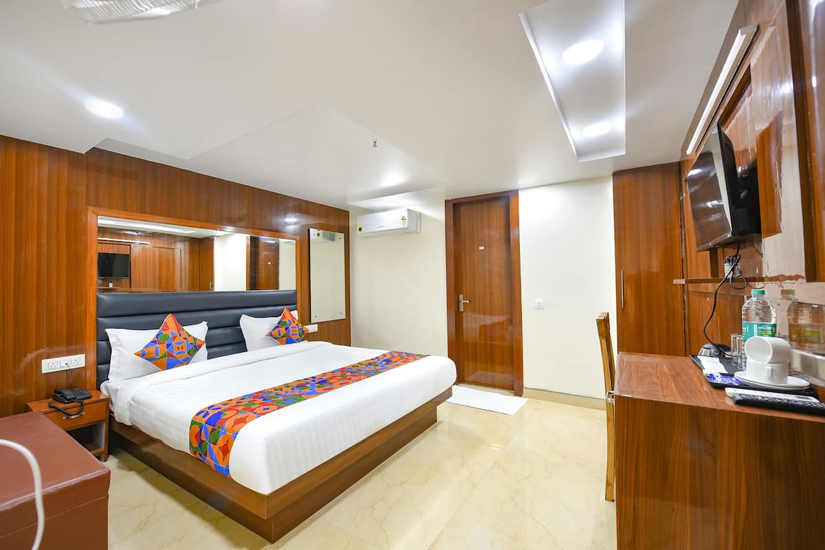 Una habitación de hotel con una cama grande, paneles de madera, un televisor, un escritorio con una silla y la puerta del baño.