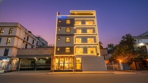 A modern hotel with a prominent sign, multiple floors, and a well-lit entrance. - Fabhotel Mona International (New Delhi)