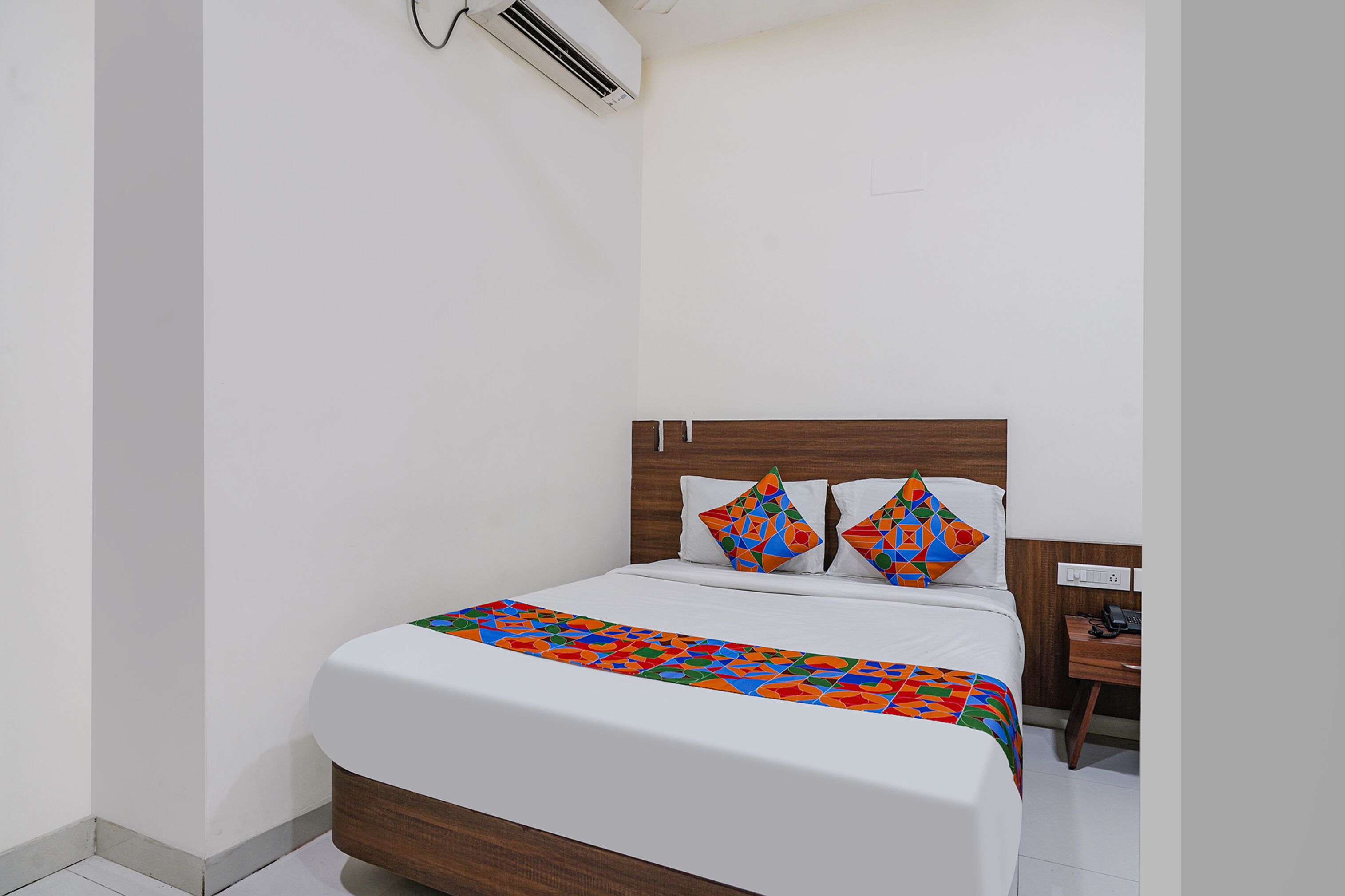 Una cama bien hecha con un edredón de estampado geométrico y dos almohadas decorativas.