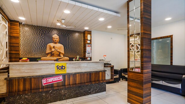 A hotel reception area with a Buddha statue, a reception desk, and a seating area. - Fabhotel V Grand (Vijayawada)