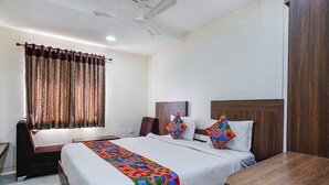 A hotel room with a large bed, a wooden nightstand, a desk, a chair, and a ceiling fan. - Fabhotel V Grand (Vijayawada)