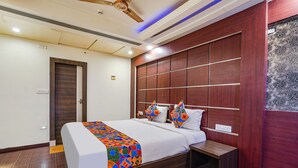 Una habitación de hotel moderna con una cama grande, un cabecero de madera, una mesita de noche y un ventilador de techo.