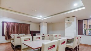 Un comedor con una mesa larga y varias sillas, un ventilador de techo y una ventana con cortinas.