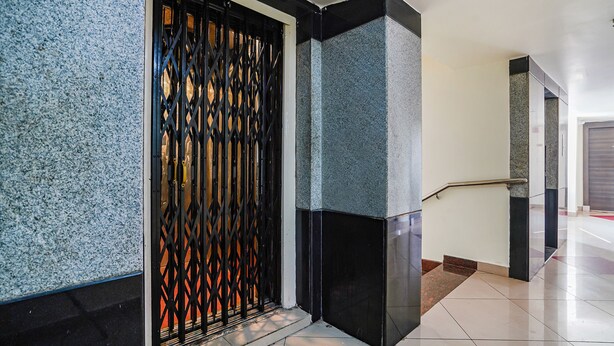 Un interior moderno con una escalera, una reja de metal y un suelo de baldosas.
