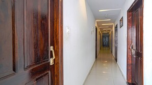 A hallway with wooden doors and white walls. - Fabhotel Hamsa The Right Choice (Hyderabad)