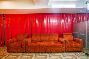 A three-seater sofa with a quilted pattern, positioned in front of a red curtain backdrop. - Fabhotel Hamsa The Right Choice (Hyderabad)