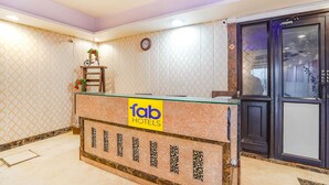 Een receptiebalie met een 'fab hotels' bord, een klok en een deur met een keypad.