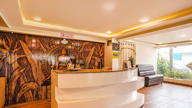 Uma área de recepção com painel de parede de madeira, balcão curvo, sofá e planta em vaso.