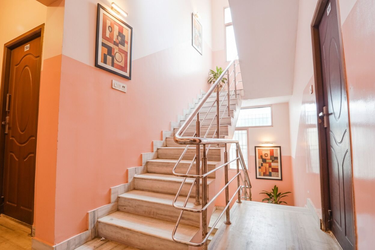 A staircase with metal railings, a wooden door, and a wall with framed artwork.