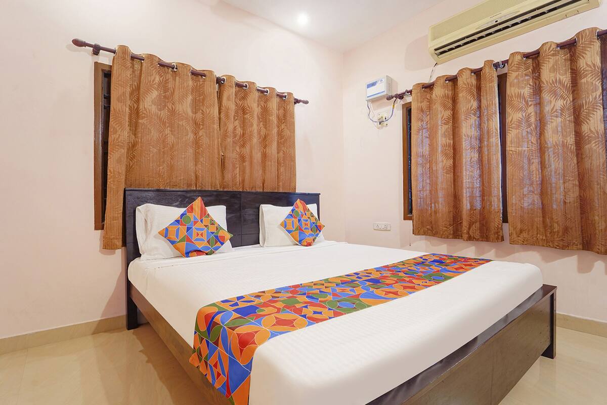 A neatly made bed with a colorful bedspread, wooden headboard, and matching curtains.
