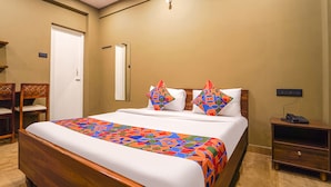A hotel room with a bed, a nightstand, a chair, and a door. - Fabhotel Hn Pear View Stays (Kodaikanal)