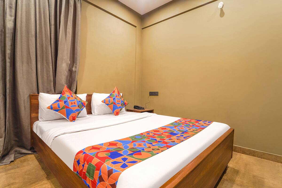 Cama bem arrumada com colcha estampada em padrão geométrico e duas almofadas decorativas.