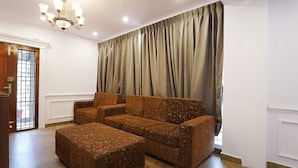 A living room with a sofa set, ottoman, and a chandelier. - Fabhotel Hn Pear View Stays (Kodaikanal)