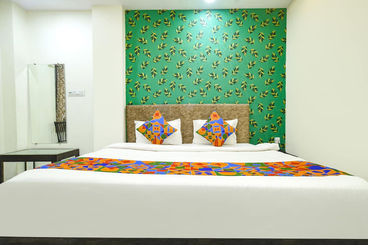 A hotel room with a bed, a nightstand, and a mirror.