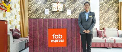 A hotel reception area with a 'fab express' sign, a reception desk, a sofa, a bed, and a wall with a patterned design.