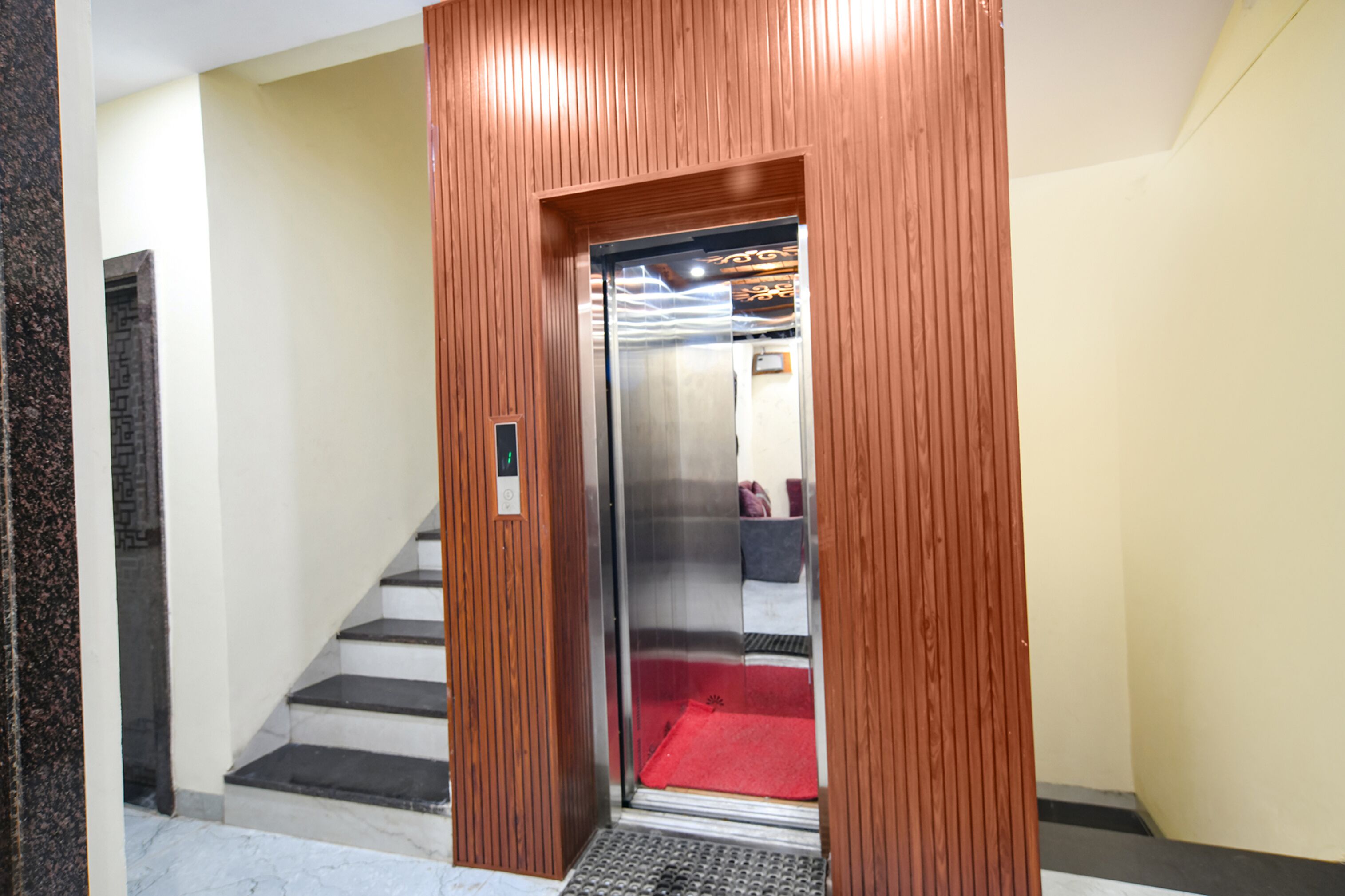 Un ascenseur doté de panneaux en bois, d’un tapis rouge et d’un panneau de commande.