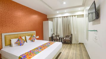 A hotel room with a bed, a desk, a chair, a television, and a window with curtains.
