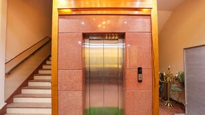 An elevator with a green carpet at the bottom, a wooden frame, and a metal door. - Fabhotel Uday Villa (Kanpur)