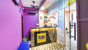 Een receptie met een 'fab hotels' bord, een plafondventilator en een incheckbalie.