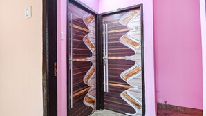 Een hoekzaal met een roze wand en een houten deur met een bijzonder ontwerp.