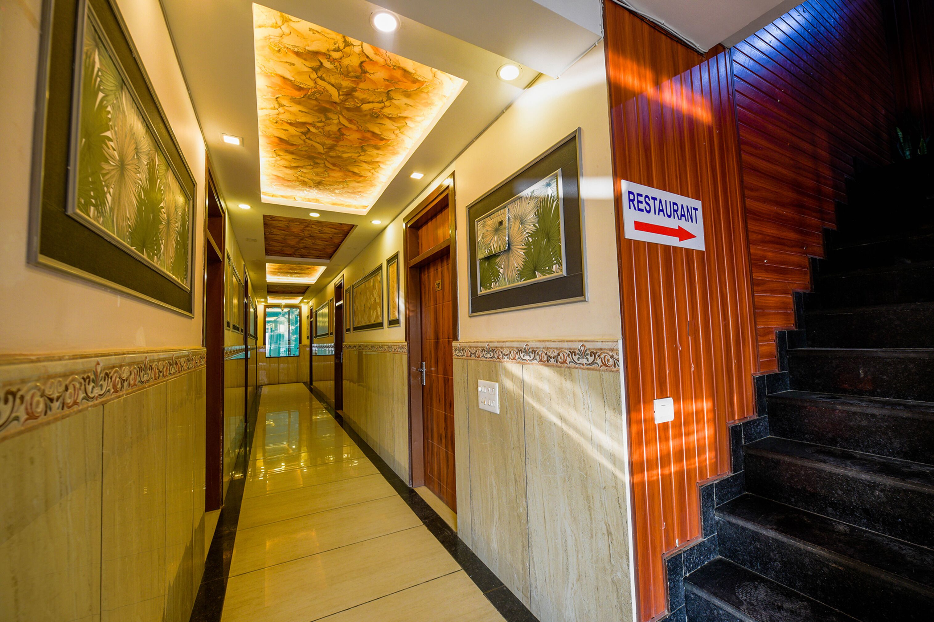 A hotel hallway with a sign indicating a restaurant direction, wooden paneling, and framed artwork on the walls.