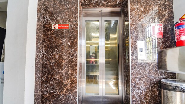 An elevator with a 'No Smoking' sign, a fire extinguisher, and a 'Welcome' mat. - Fabexpress Silver Palace (Chennai)