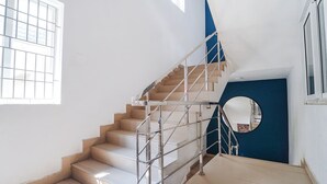 A staircase with metal railings, a blue wall, and a circular mirror. - Fabexpress Silver Palace (Chennai)