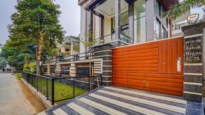 A modern building with a wooden gate, a nameplate, and a paved area with a striped pattern. - Fabhotel White Elephant (Greater Noida)