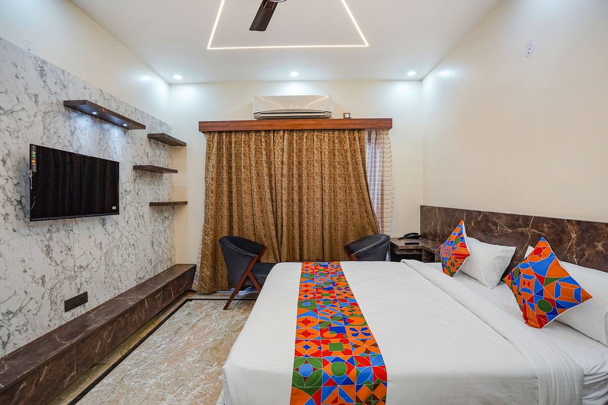 A hotel room with a bed, a TV mounted on the wall, a desk, and a chair.