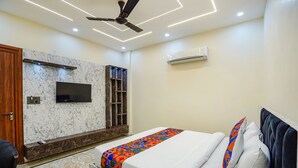 A modern bedroom with a bed, a TV mounted on the wall, and a ceiling fan. - Fabhotel White Elephant (Greater Noida)