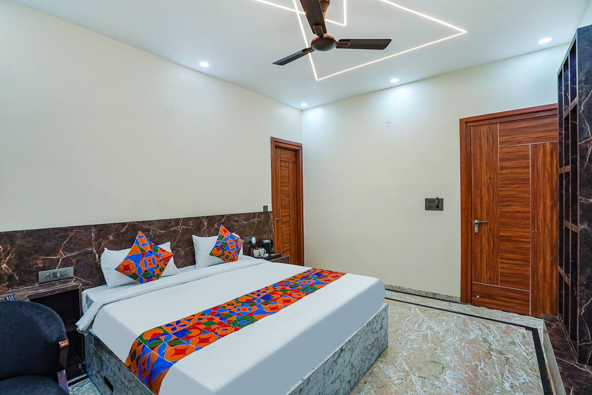 A modern hotel room with a large bed, a ceiling fan, and wooden doors.