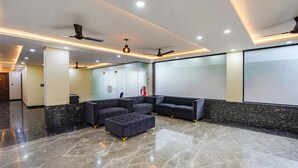 A modern lobby with a marble floor, black sofas, and ceiling fans. - Fabhotel White Elephant (Greater Noida)