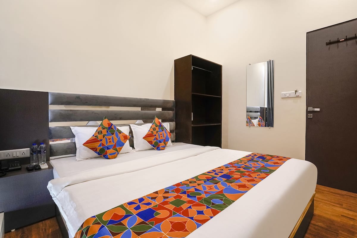 A hotel room with a bed, a wardrobe, a nightstand, and a mirror.