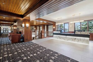 A spacious lobby with a wooden ceiling, a reception desk with marble, and a patterned carpet. - Highlands Lodge 303 - 3 Bedroom Residence (Beaver Creek)