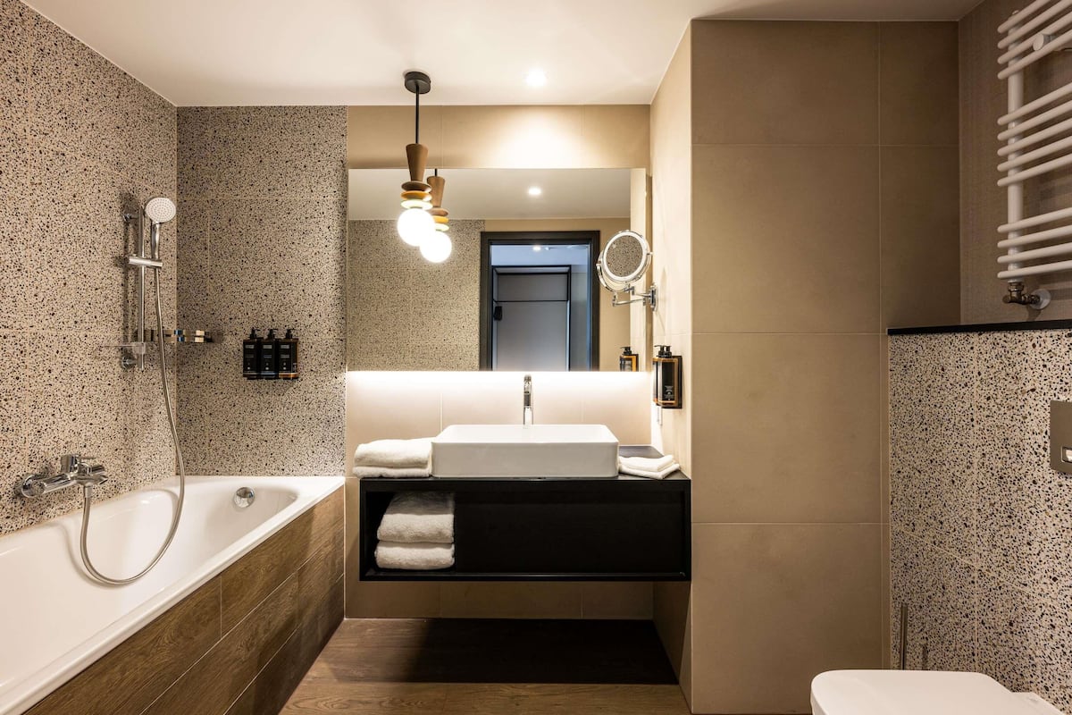Une salle de bain moderne avec une baignoire sur pieds, un meuble-lavabo avec un miroir et des toilettes.
