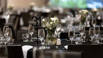 A banquet table with numbered place settings, a vase with flowers, and a black tablecloth.