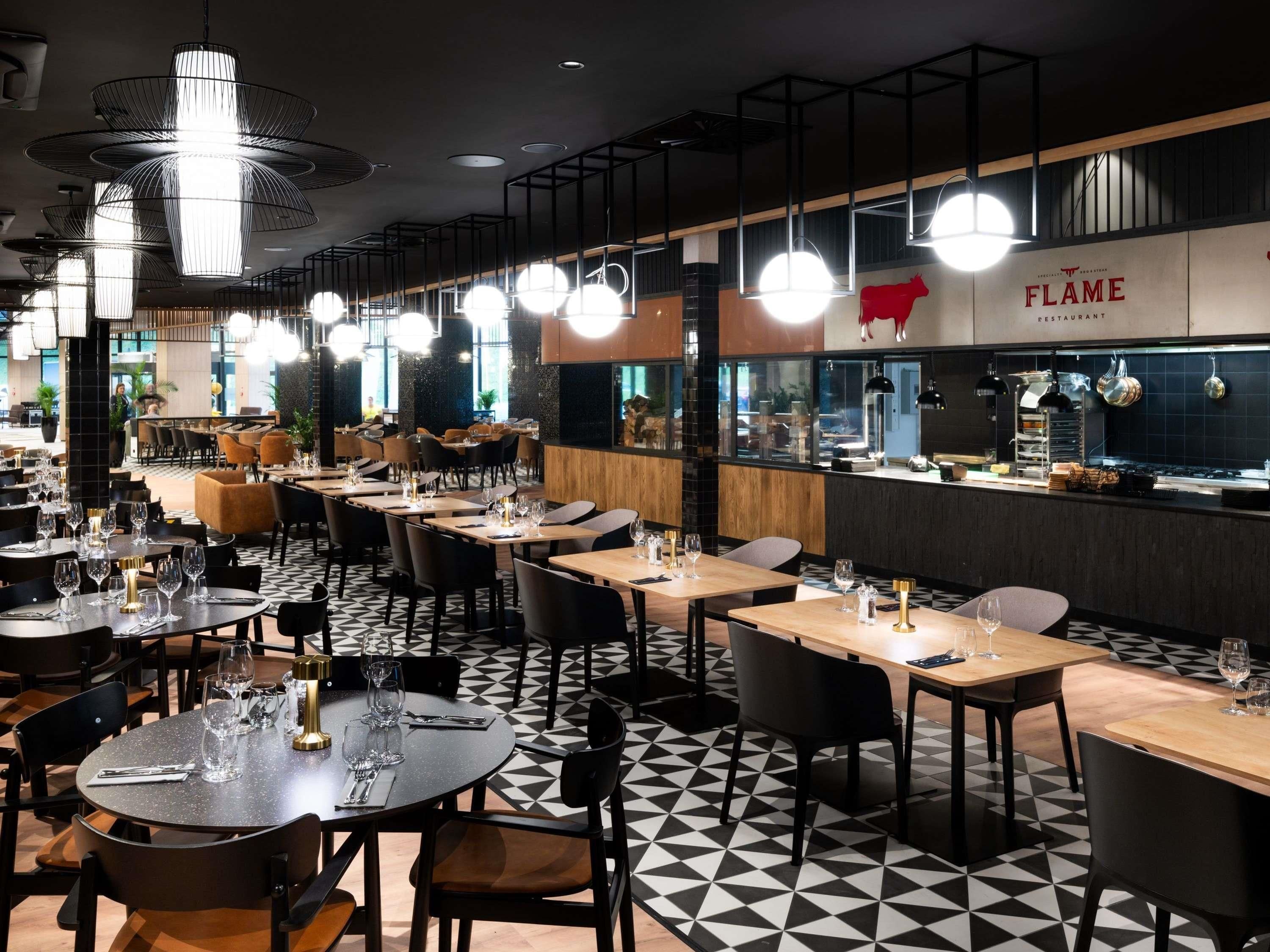 Un interior de restaurante con varias mesas, sillas e iluminación colgante.