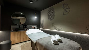 Une salle de spa équipée d’une table de massage, d’un miroir rond, d’armoires en bois et d’œuvres d’art murales.