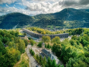 Ein modernes Gebäude mit gewölbter Dachform, umgeben von üppiger Vegetation und Hügeln.