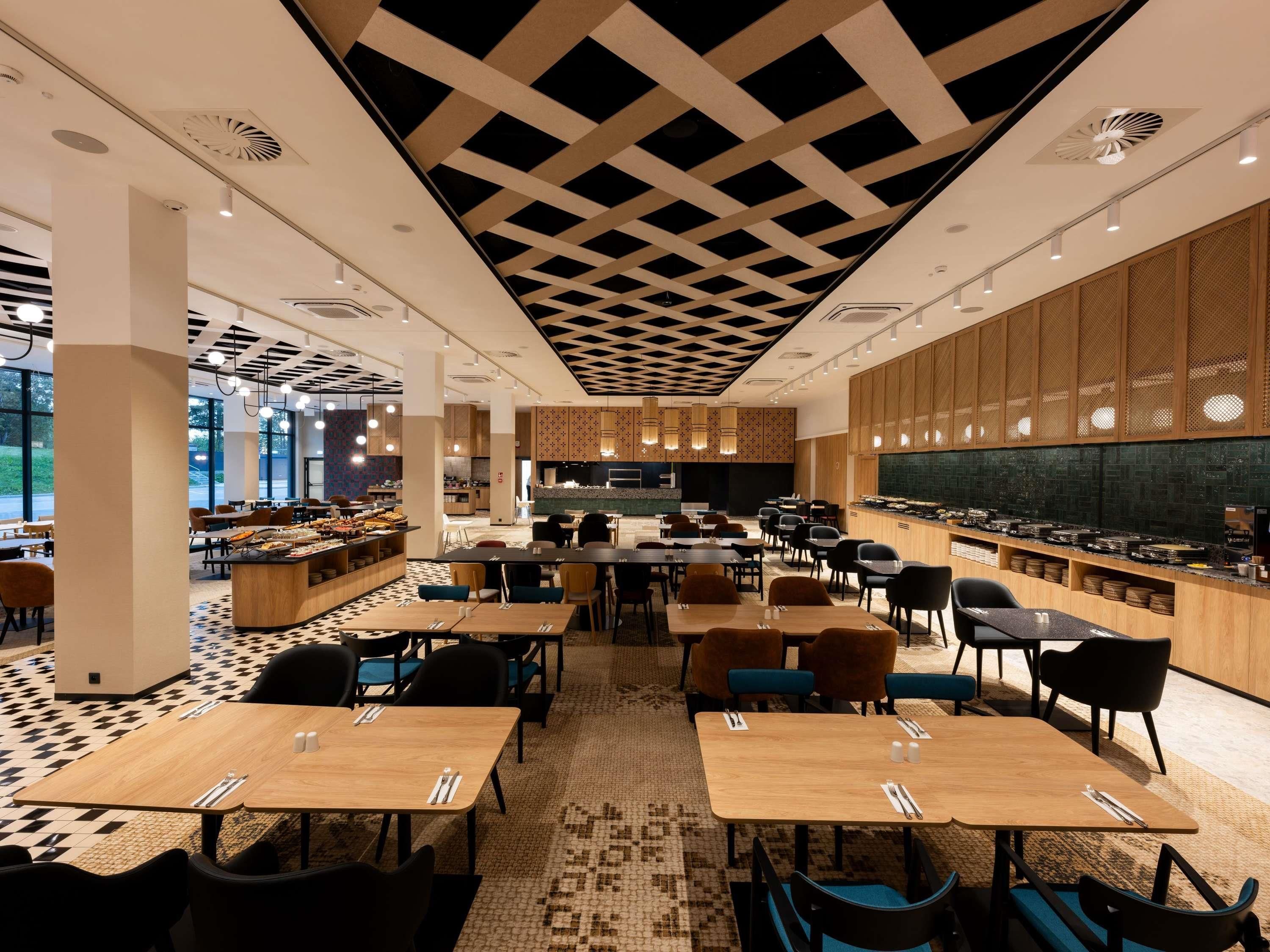 A modern restaurant with a checkered ceiling, wooden panel walls, and a buffet area.