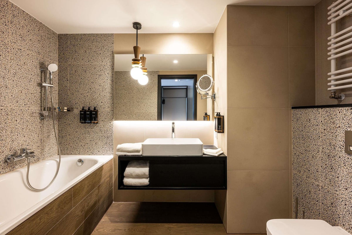 Ein modernes Badezimmer mit freistehender Badewanne, einem Waschtisch mit Spiegel und einer Toilette.