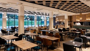 Un vaste espace dédié à la salle à manger, avec de nombreuses tables et chaises, de grandes fenêtres et un design moderne au niveau du plafond.
